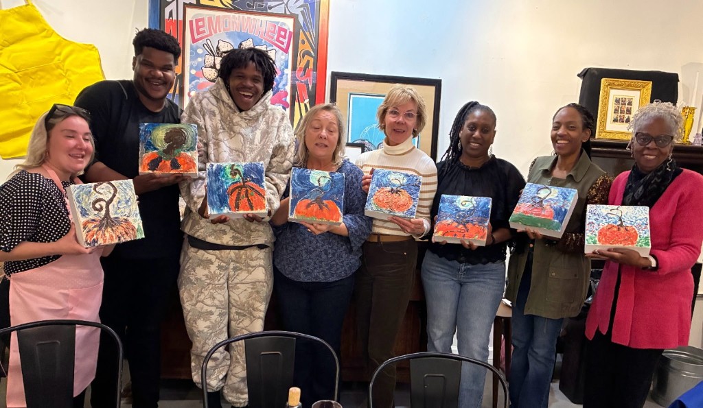 Guests from the first Cake and Sip, each holding a pumpkin painting